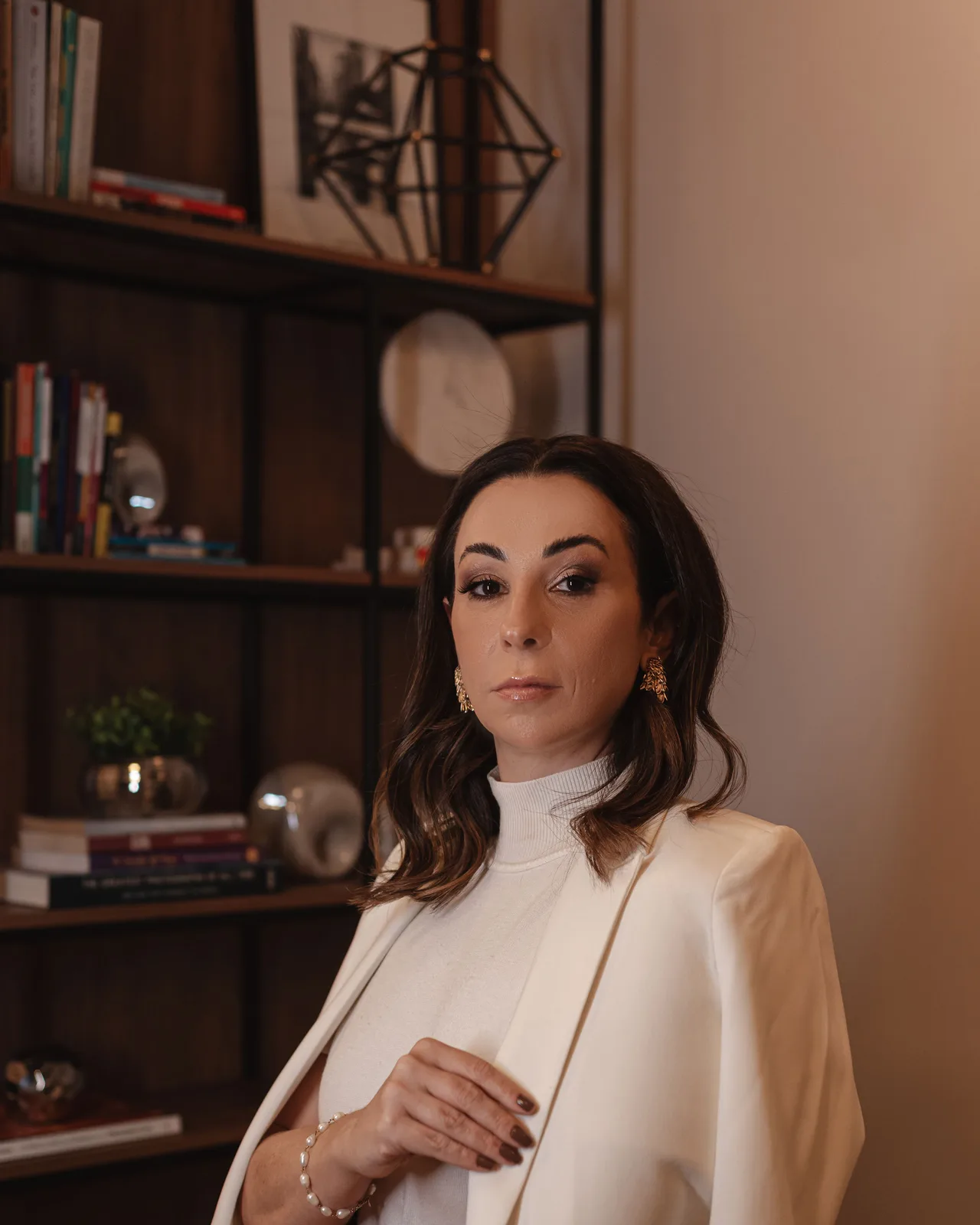 Dra. Natália Sanfins de pé, em frente à estante do escritório