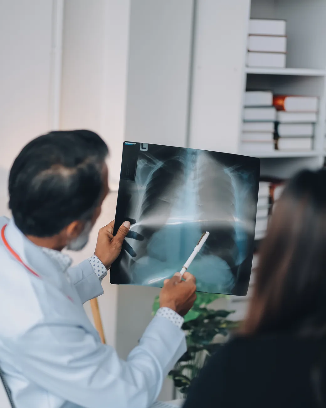 Médico mostra uma radiografia à paciente no consultório