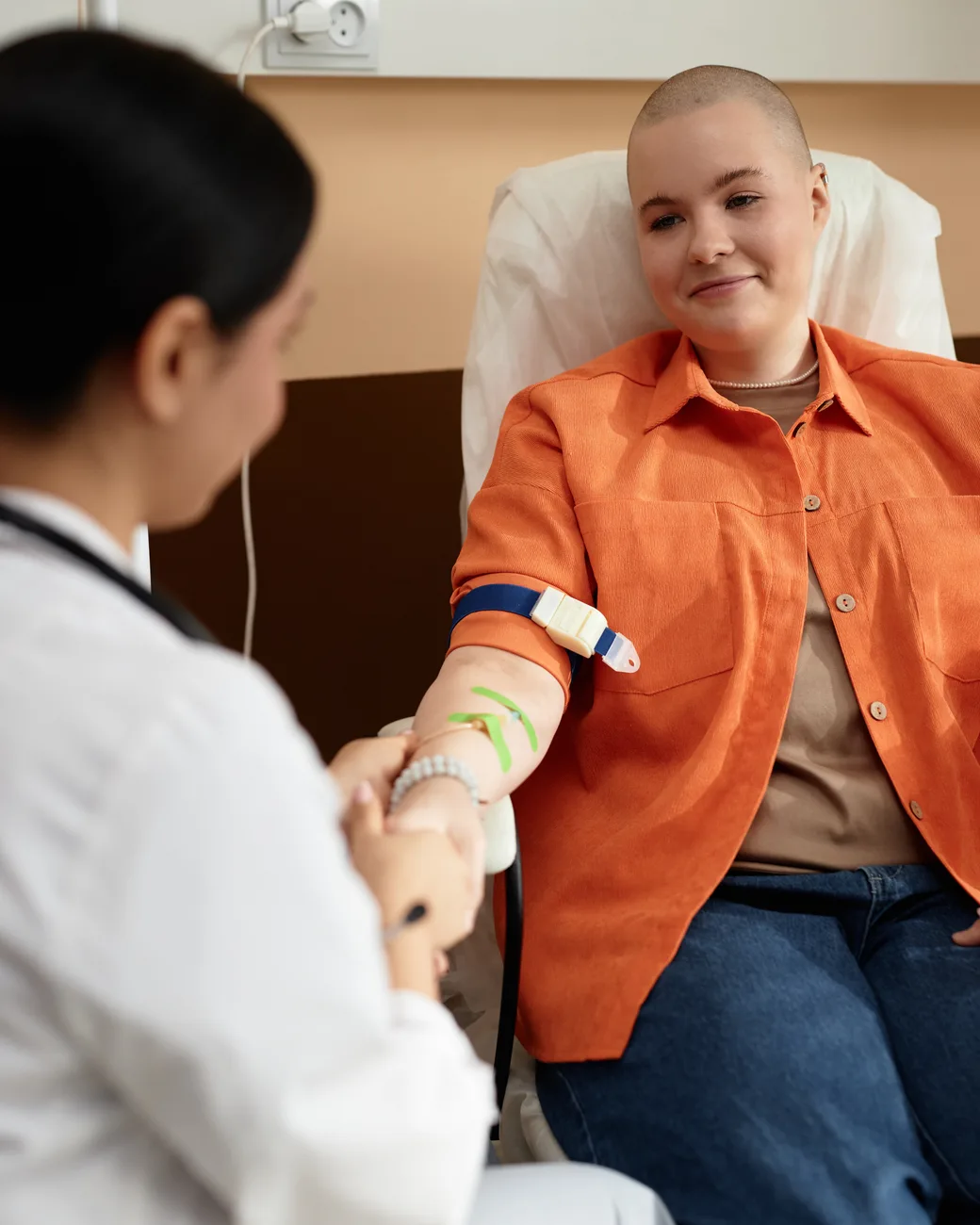 Paciente sorri durante sessão de quimioterapia, acompanhada pela médica